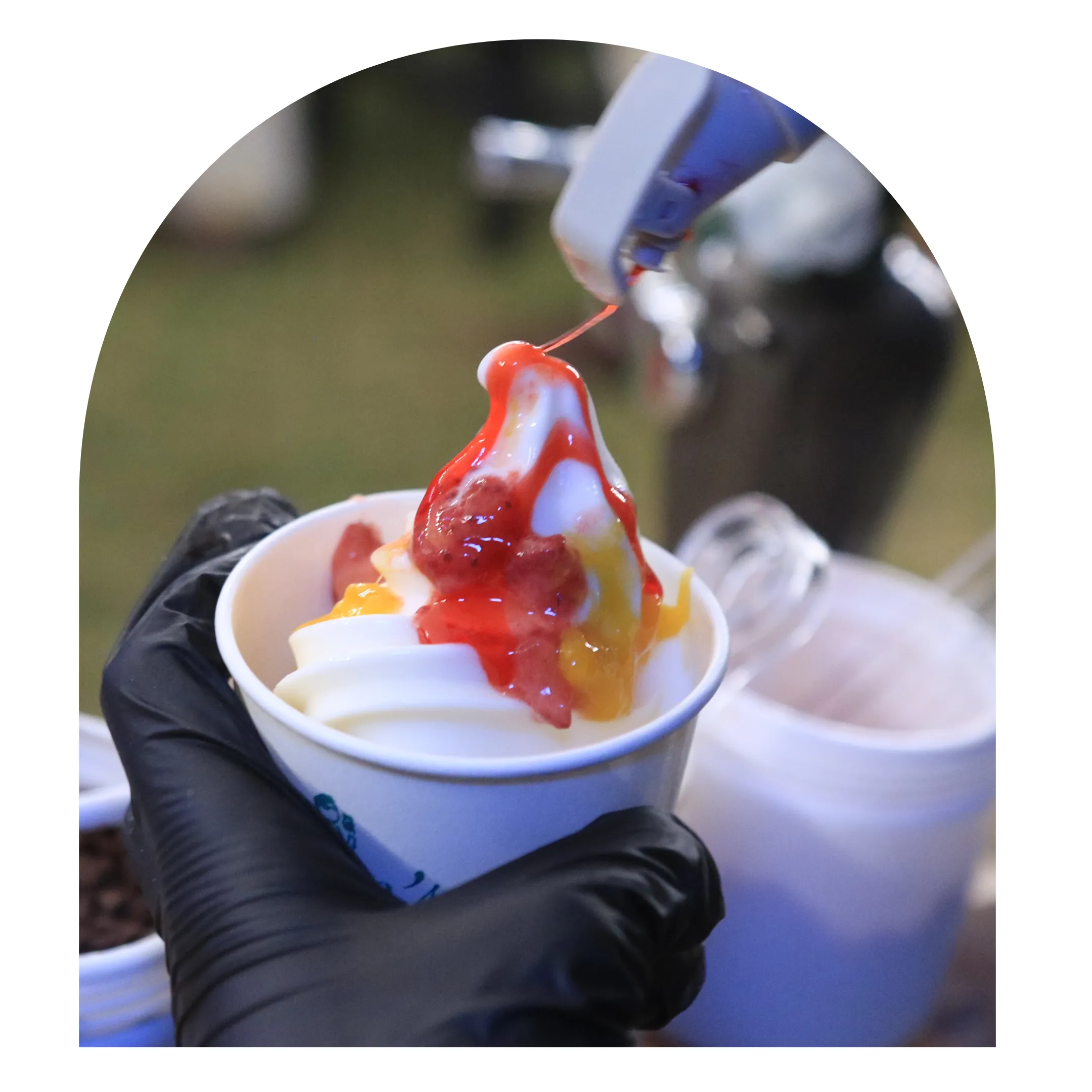 Strawberry syrup being drizzled onto a fresh Dan's Froyo frozen yogurt cup