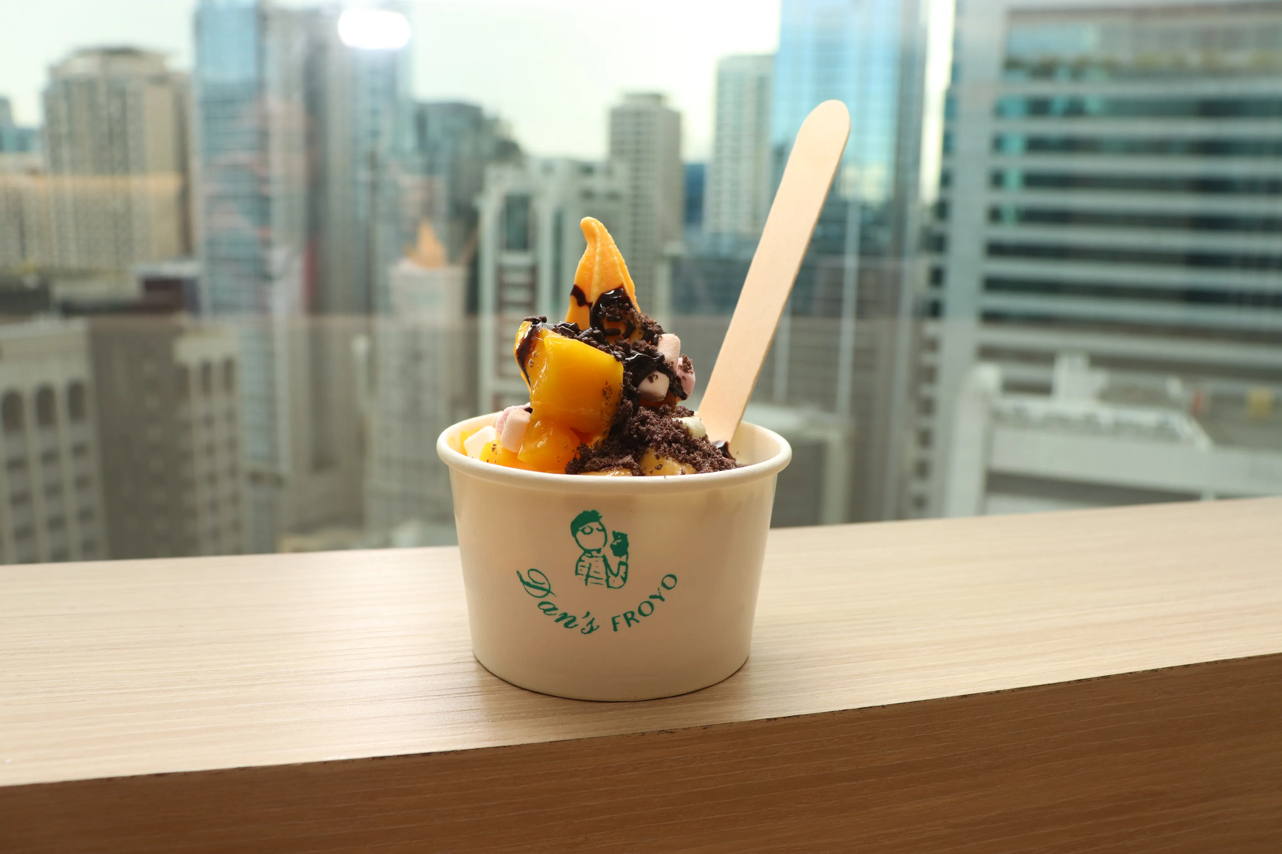 Close-up of a Dan's Froyo frozen yogurt cup with chocolate and mango toppings